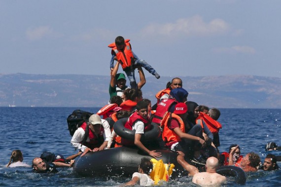 A refugee raises a child into the air as Syrian and Afghan refugees are seen on and around a dinghy that deflated some 100m away before reaching the Greek island of Lesbos, September 13, 2015. Of the record total of 432,761 refugees and migrants making the perilous journey across the Mediterranean to Europe so far this year, an estimated 309,000 people had arrived by sea in Greece, the International Organization for Migration (IMO) said on Friday. About half of those crossing the Mediterranean are Syrians fleeing civil war, according to the United Nations refugee agency. REUTERS/Alkis Konstantinidis